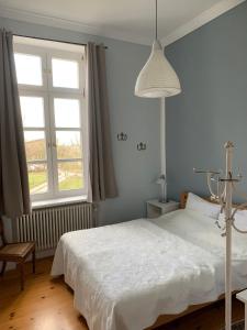 a bedroom with a white bed and a window at Schloss Lelkendorf, Fewo Hoppenrade in Lelkendorf
