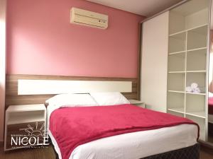 um quarto com uma parede vermelha e uma cama em Residencial Nicole em Florianópolis