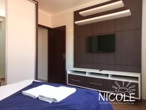 um quarto com uma cama e uma televisão na parede em Residencial Nicole em Florianópolis