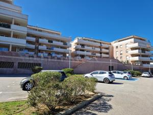 un estacionamiento con autos estacionados frente a un edificio en Studio cosy proche toutes commodités avec parking gratuit, en Mezzavia