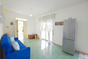 - un salon avec un canapé bleu et un réfrigérateur dans l'établissement Villa Sud Sicily, à Santa Maria Del Focallo