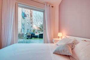 um quarto com uma cama branca e uma grande janela em Le 002 - T3 climatisé avec terrasse em Marselha