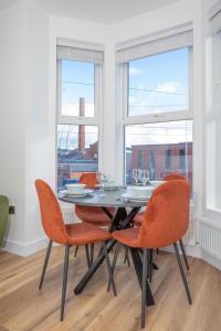 a dining room with a table and orange chairs at Eastside Capital Apartments in Belfast