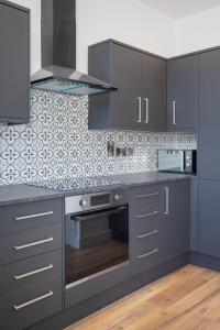 a kitchen with gray cabinets and a stove at Eastside Capital Apartments in Belfast