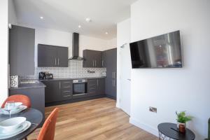 a kitchen with black cabinets and a table and a dining room at Eastside Capital Apartments in Belfast