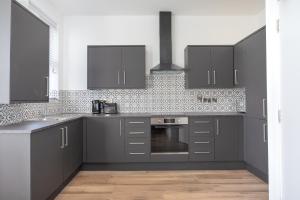 a kitchen with gray cabinets and a stove top oven at Eastside Capital Apartments in Belfast