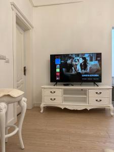 telewizor z płaskim ekranem siedzący na górze białego centrum rozrywki w obiekcie FSF Boutique Apartament w mieście Timişoara