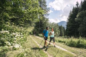 un uomo e una donna che sciano su una pista di Chalet Alpenrose Bio Wellness Naturhotel a Cogolo