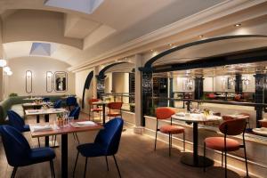a restaurant with tables and chairs and a kitchen at Duo Milan Porta Nuova, a Tribute Portfolio Hotel in Milan