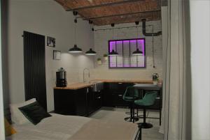 a bedroom with a bed and a kitchen with purple lights at Apartamenty STARA PIEKARNIA in Płock