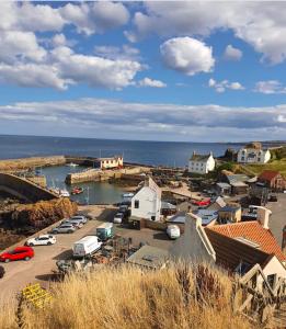 a small town with cars parked in a harbor at Romantic luxury Cottage right next to the ocean in Saint Abbs