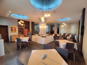 スコピエにあるプレミア ホテルの白いテーブルと椅子、青い照明が備わるレストラン