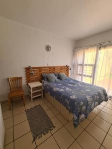 マーゲートにあるUvongo cabanasのベッドルーム1室(ベッド1台、椅子、窓付)