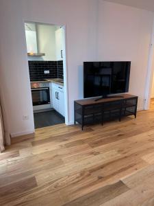 uma sala de estar com uma televisão grande e um piso de madeira em 44qm Apartment in Pempelfort em Dusseldorf