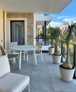 patio z białym stołem, krzesłami i palmami w obiekcie L'apart'83 - T2 classé 5 étoiles - Belle vue sur la baie du Lazaret w mieście Saint-Elme