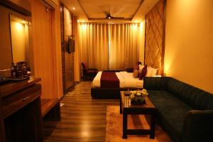 Perfectstayz Premium @Harkipauri Road في حاريدوار: غرفه فندقيه بسرير واريكه