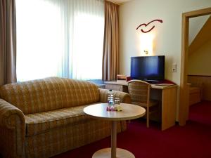 a living room with a couch and a table with a tv at Seehotel Weit Meer in Waren