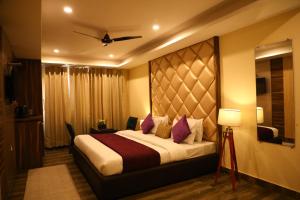 a hotel room with a large bed with purple pillows at Perfectstayz Premium @Harkipauri Road in Haridwār