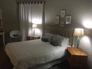 1 dormitorio con 1 cama grande y 2 lámparas. en Bramber Cottage Hogsback, Living With Joy!, en Hogsback