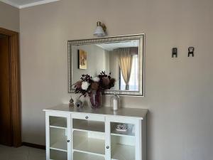 a white cabinet with a mirror and a vase of flowers on it at Lovely Apartment in Parma