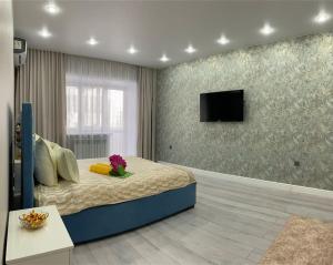 a bedroom with a bed and a tv on a wall at VIP апартаменты в центре города in Kostanay