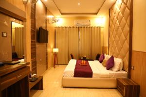 ハリドワールにあるPerfectstayz Premium @Harkipauri Roadのベッドとテレビが備わるホテルルームです。