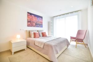 a bedroom with a bed with a chair and a window at WIOLA SeaView Apartment by MOJE Holiday in Lagos +18 photos