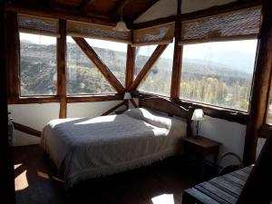 a bedroom with a bed in a room with windows at Cabaña El Cóndor - Complejo El Taller in Potrerillos