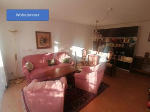 ein Wohnzimmer mit einem rosa Sofa und Stühlen in der Unterkunft Wohnidyll in Zeuthen bei Berlin in Zeuthen