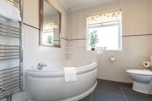 y baño con bañera, aseo y lavamanos. en Cheerful 3-bedroom Douglas house with patio en Southampton