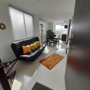 a living room with a black leather couch and a table at Parque del Café Apartamentos con Piscina in La Tebaida