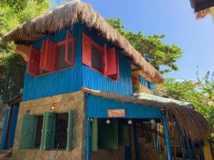 a blue building with red windows and a straw roof at Beach House-Casita in Calatagan with pool ( for 6) in Calatagan