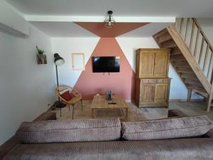 a living room with a couch and a tv on a wall at Gîte Sud Ardèche in Vinezac