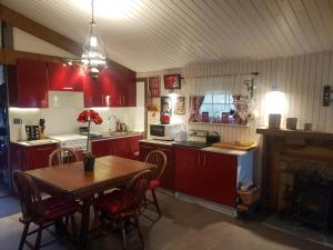a kitchen with red cabinets and a table with chairs at Namaste Gîte in Plounevez-Quintin