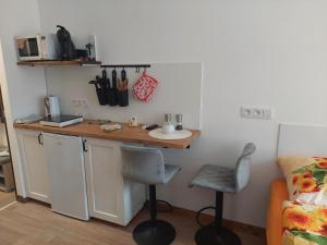 eine Küche mit einer Theke mit einer Spüle und 2 Hockern in der Unterkunft Apartmán U dvou slunečnic in Benešov nad Černou