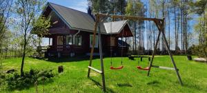 une cabane en rondins avec des balançoires en face d'une maison dans l'établissement Kivitasku, à Kalajoki