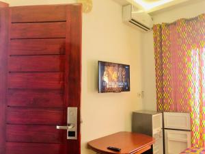um quarto com uma porta e uma televisão na parede em GRACE LODGE em Lomé
