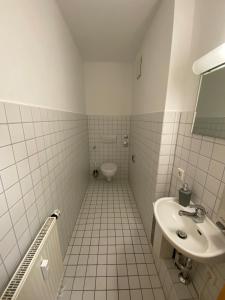 a white tiled bathroom with a sink and a toilet at Wohnung in Nürtingen in Nürtingen