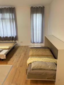 two beds in a room with wooden floors and windows at Wohnung in Nürtingen in Nürtingen