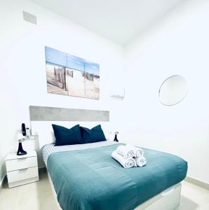 Alojame Valencia في فالنسيا: غرفة نوم بسرير ازرق عليها مناشف