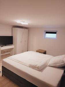 um quarto com uma grande cama branca e uma televisão em E&O em Gilching