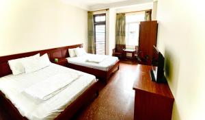 a hotel room with two beds and a television at Nam Khánh Motel in Hanoi