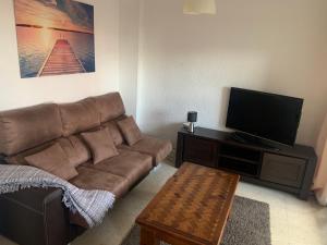a living room with a brown couch and a flat screen tv at Gibraltar Rock View in La Línea de la Concepción