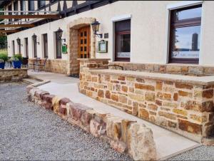 a stone retaining wall in front of a building at Hotel Waldquelle - Baumhaushotel Aerzen in Aerzen