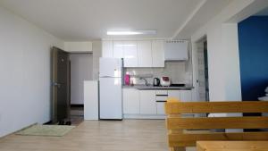 a kitchen with white cabinets and a white refrigerator at Ein House in Gongju