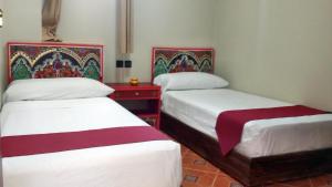 タンジェにあるホテル マラムのベッド2台と赤いテーブルが備わる客室です。