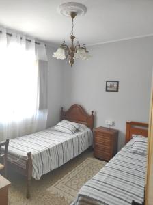 1 dormitorio con 2 camas y lámpara de araña en Casa familiar con finca privada (Orolterra), en Viveiro
