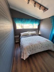 コキンボにあるMi Estanciaのベッドルーム1室(ベッド1台、青いカーテン付きの窓付)