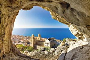 una vista su una città attraverso una formazione rocciosa di Perla Blu a Cefalù