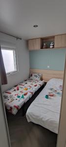 - 2 lits dans une petite chambre avec fenêtre dans l'établissement Mobil Home Palmiers 1, à Valras-Plage